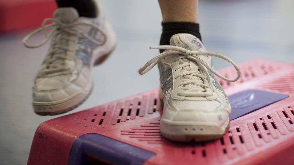 Nahaufnahme eines Sportschuhs auf einem pinken Stepper im Fitnessstudio.